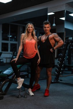 Güzel, ince bir kız ve spor salonunda dövmesi olan kaslı vücutlu yakışıklı bir adam. Güzel spor çifti ve sağlıklı yaşam tarzı