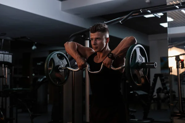 身穿黑色运动服的身材魁梧英俊的男子健美运动员在健身房做运动和训练 — 图库照片