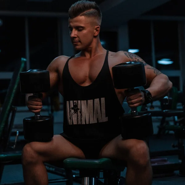 Muscular Homem Forte Sportswear Preto Sentado Segurando Halteres Exercitando Ginásio — Fotografia de Stock