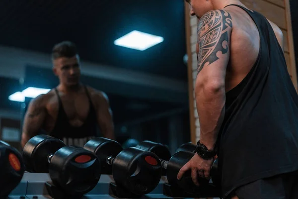 强壮的年轻英俊健美男子 有纹身和肌肉的身体训练在健身房 哑铃练习 — 图库照片