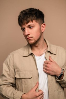 Stüdyoda şık bej ceketli ve beyaz tişörtlü şık görünümlü genç adam. Dış giysili adam