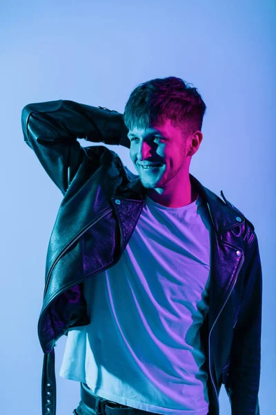 明るい青とピンクの光とスタジオでクールなファッショナブルなレザージャケットの幸せなハンサムな若いヒップスター男 スタイル ファッション 男性の美しさ — ストック写真
