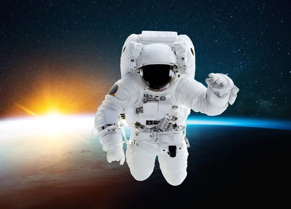 宇航员在蓝色地球的背景下 带着令人惊奇的日落和星星 在宇宙中飞行 在外层空间执行飞行任务和升空的空间人 — 图库照片