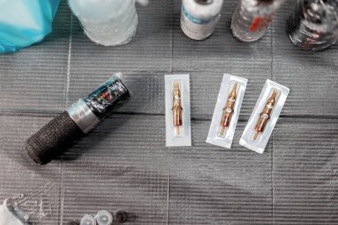 Steril bir çalışma alanında dövme yapmak için gerekli aletler. Masasında boya ve iğne olan bir dövme makinesi. Dövme sanatçısı