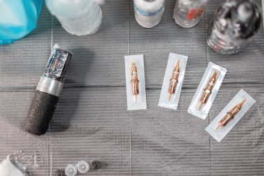 Makineli dövme aletleri, boyalar, ambalajlar ve yeni iğneler. Dövme sanatçısının steril işyeri, üst görünüm