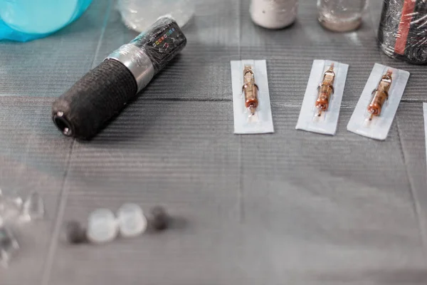 Dövme aletleri olan bir masa. Usta 'nın çalışma odası daktilo, iğne ve boya ile