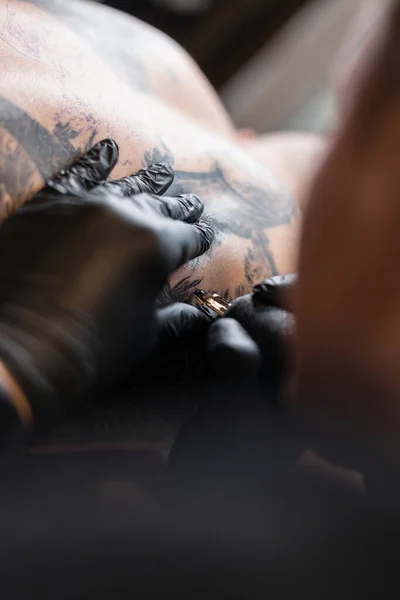 man professional tattoo artist with black gloves making a tattoo, close-up