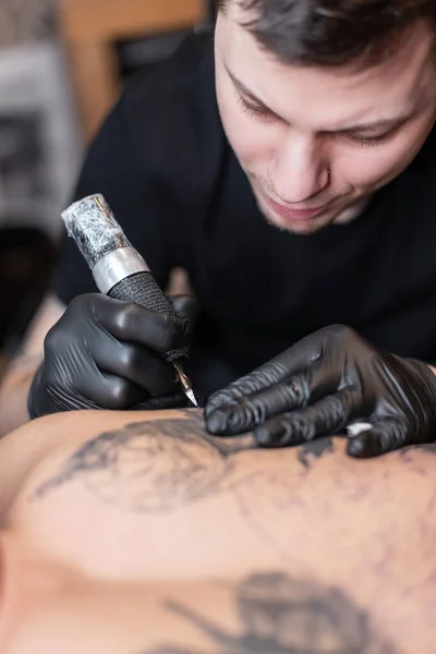 professional man tattoo artist stuffs tattoos, close-up. Modern tattoo machine in operation