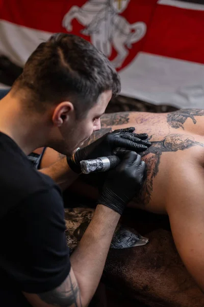 man tattoo artist works in a studio and stuffs tattoo on a man\'s back