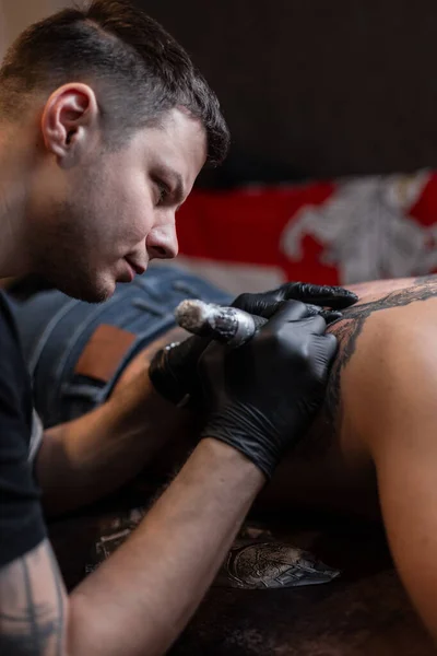 Tattoo artist professional stuffing a tattoo on a male body