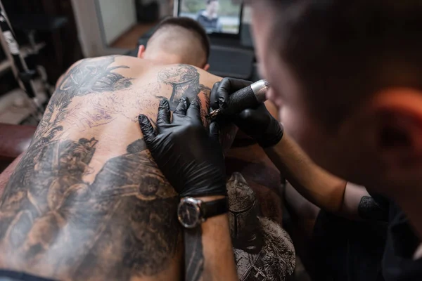 Homem Hipster Tatuagem Artista Desenha Tinta Pele Com Uma Máquina — Fotografia de Stock