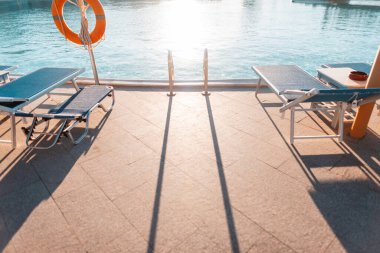 Metal tırabzanlar inen güzel bir havuz, plaj şamandırası ve gün batımında bir can simidi. Yüzme ve yaz tatili konsepti