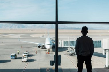 Koruyucu maskeli bir gezgin uçağın arka planında yolcu alımını bekliyor. Seyahat ve koronavirüs konsepti. Kalkıştan önce uçak hazırlığı
