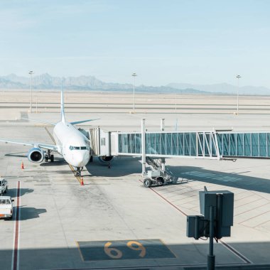 Havaalanında iniş köprüsü olan güzel bir uçak. Arka planda dağlar, çöl ve mavi gökyüzü. Uçağı kalkışa hazırlıyorum. Havayolu konseptiyle seyahat