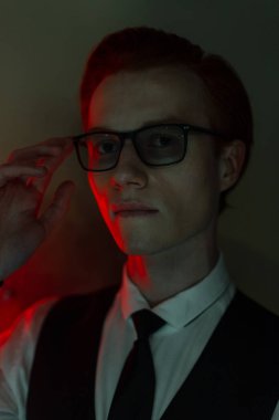 Moda dünyasından gözlüklü, yeşil ve kırmızı ışıklarda gömlek ve kravat takan yakışıklı bir genç adamın renkli portresi. Klasik ofis erkek tarzı.