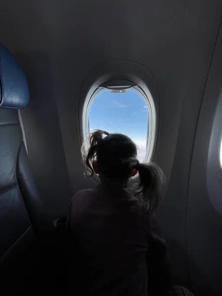 Dziewczynka Lata Samolotem Patrzy Przez Okno Koncepcja Bezpiecznej Podróży — Zdjęcie stockowe