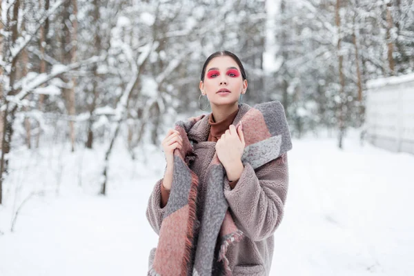 时尚而富有创造力的年轻女性模特 穿着时尚的冬衣 头戴毛皮外套 戴着围巾 走在雪地的冬日公园里 — 图库照片