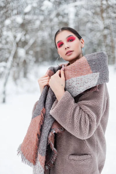 在挪威的一个冬季森林里 一位穿着时髦服装 穿着保暖外套和围巾的时髦而美丽的斯堪的纳维亚年轻女子 — 图库照片