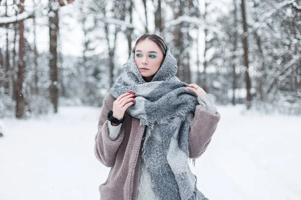 在挪威的一个冬季森林里 穿着时髦的冬季保暖服装 穿着外套和围巾的漂亮的斯堪的纳维亚少女在散步 — 图库照片