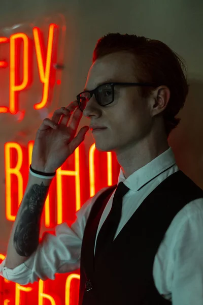 Stylish Young Man Fancy Clothes Neon Red Light Puts Glasses — Stock Photo, Image