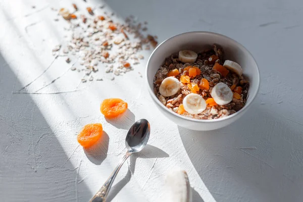 Sabahın erken saatlerinde kurutulmuş kayısı ve muzlu beyaz tabakta nefis müsli. Sağlıklı kahvaltı.