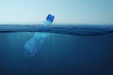 Çöp plastik şişesi mavi deniz suyunda su altında yüzer. Çevre ve okyanusların kirliliği.