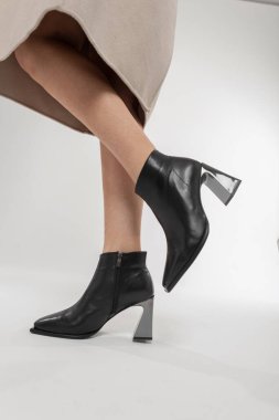 Stüdyoda zarif klasik deri ayakkabılı kadın bacakları, yakın plan. Havalı siyah ayakkabılı, bej ceketli, şık bir kız.