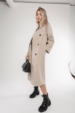 Tam boy portre, bej rengi klasik ceket, siyah deri ayakkabı ve el çantası giyen zarif bir kadın. Moda stüdyosu çekimi