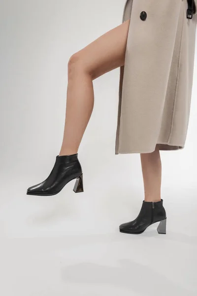 优雅漂亮的女模特 穿着米黄色外套和黑色经典时尚皮鞋 背景是白色的 性感的女性腿和时髦的高跟鞋 — 图库照片