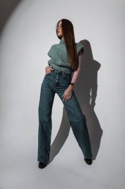 Stüdyoda kotlu ve örgü süveterli şık ve alımlı kıyafetler içinde şık ve çekici bir kız.