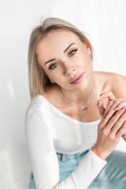 Şirin yüzlü, yeşil gözlü, beyaz tişörtlü ve kot pantolonlu güzel bir genç kadının portresi stüdyoda kameraya bakıyor. Güneş ışığındaki kız