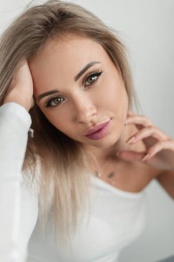 Beyaz tişörtlü, beyaz arka planda güzel gözleri ve dudakları olan güzel sarışın bir kadının portresi. Güzel bir kadın yüzü