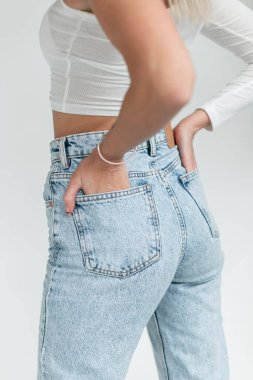 Modaya uygun kot pantolonlu şık bir kadın ellerini ceplerinde tutuyor, yakın plan. Kadın Denim Giysileri