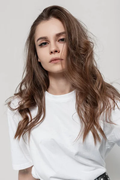 穿着灰色背景的白色T恤衫 有着自然美景和发型的时髦而美丽的年轻姑娘 — 图库照片