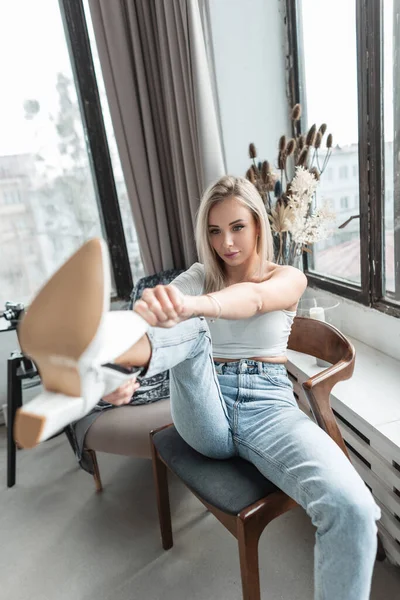 Beautiful Young Blonde Woman White Shirt Blue Jeans Sits Chair — 스톡 사진