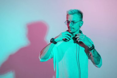 Stüdyoda gözlüklü ve kulaklıklı, yaratıcı ışığı olan şık, genç bir hippi.