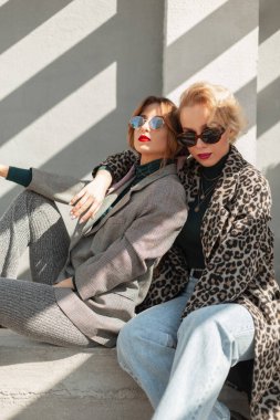 Leopar ceketli ve güzel takım elbiseli iki kadın. Moda sonbahar oturumu fotoğrafı