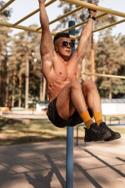 Bardan sarkan ve parkta egzersiz yapan yakışıklı, atletik kaslı bir adam. Spor adamı idman konsepti