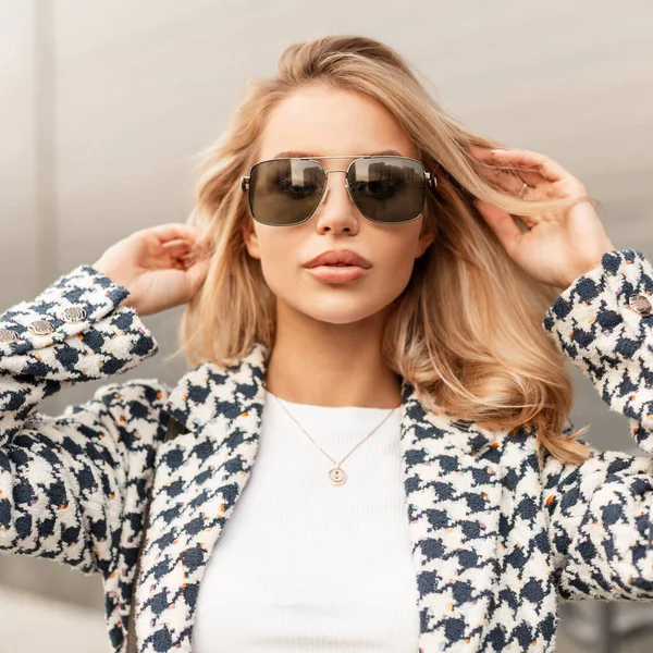 Fashion urban portrait of pretty blonde hipster woman with stylish sunglasses in elegant clothes on the street