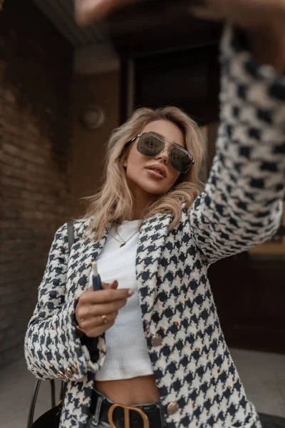 유행하는 코트에 안경을 손가방을 소녀가 사진을 만든다 — 스톡 사진