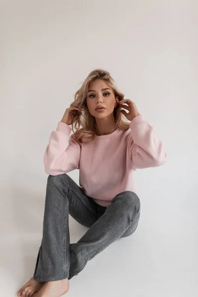 Hübsches Damenmodel Rosa Modepullover Und Vintage Jeans Sitzt Und Posiert — Stockfoto