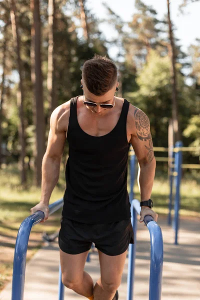 handsome sports guy trains and workout on horizontal bars in the park. Healthy lifestyle
