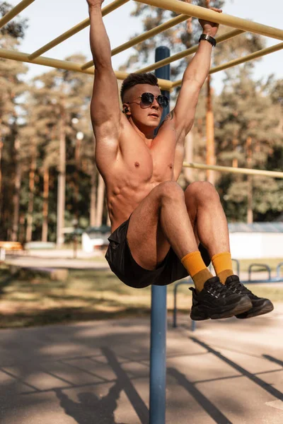 Bardan sarkan ve parkta egzersiz yapan yakışıklı, atletik kaslı bir adam. Spor adamı idman konsepti