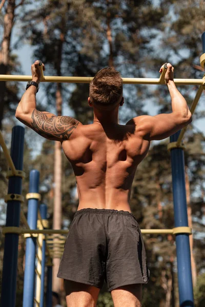 Güzel kaslı sırt egzersizi, CrossFit ve parkta egzersiz yapan yakışıklı bir adam.