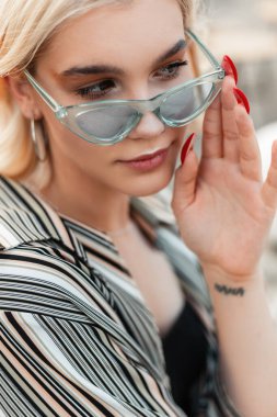 Açık havada mavi güneş gözlüklü güzel bir genç kızın moda portresi.