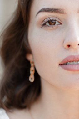 Harika kahverengi gözleri, temiz yüz derisi ve açık havada diş telleri olan güzel bir kadının yakın plan portresi.