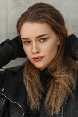 Deri ceketli, güzel, güzel bir manken. Kapüşonlu da kameraya bakıyor.