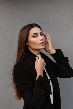 Moda mankeni, şık, siyah, şık elbiseli, gömleği ve kravatlı, sokakta gri bir arka planı olan güzel bir kadın.