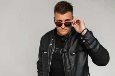 Havalı moda, siyah deri ceketli yakışıklı adam şehirde güneş gözlüğü takıyor.