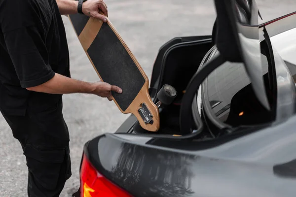 Hipster Hombre Con Ropa Negra Pone Longboard Maletero Del Coche — Foto de Stock